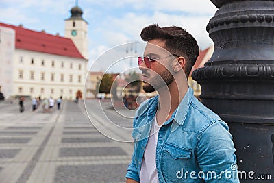 Side view of casual man standing near lighting pole Stock Photo