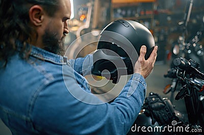 Side view shot on biker choosing new modern safety helmet in motorcycle shop Stock Photo