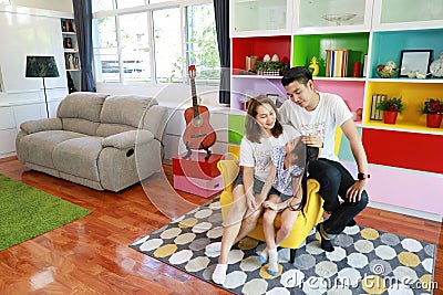 Side view shot happy asian family father, mother, and daughter sitting on sofa in colorful modern living room with relaxation and Stock Photo