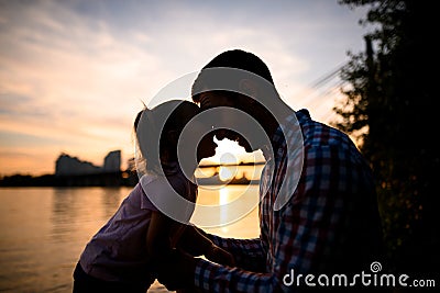 Side view on silhouettes of father and little daughter looking at each other Stock Photo