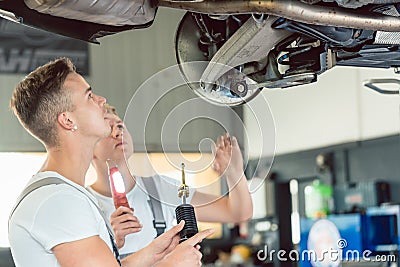 Skilled auto mechanic replacing the shock absorbers of a car in workshop Stock Photo