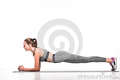 side view of smiling sportswoman doing plank exercise on yoga mat Stock Photo