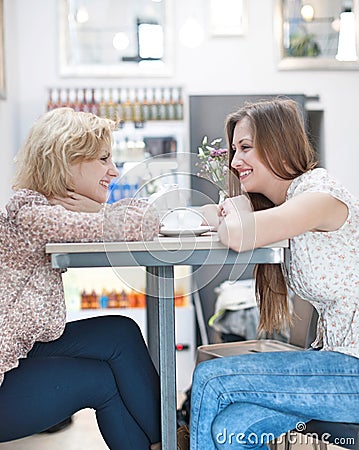 Side view of smiling young female friends sitting at cafe table Stock Photo