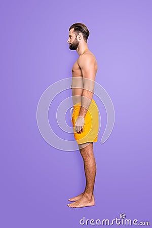 Side view snap full size fullbody portrait of attractive strong lifeguard with stubble, modern hairstyle in yellow Stock Photo