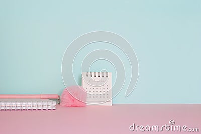 Side view on a still life. Pink fluffy pen, notepad and calendar on a pink table Stock Photo