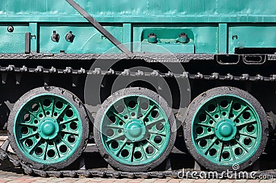Side view of the vehicle on a caterpillar track with black tracks and green wheels and a side metal wal Stock Photo