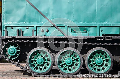 Side view of the vehicle on a caterpillar track with black tracks and green wheels and a side metal wal Stock Photo