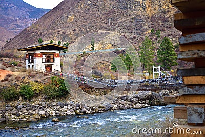 side view of walking suspension bridge with a lot of colorful prayer flags in Bhutan Stock Photo