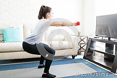 Woman going squats at home Stock Photo