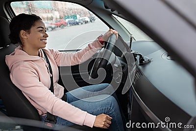 Side view of woman taxi driver sitting in transport, holding steering wheel and looking on road Stock Photo