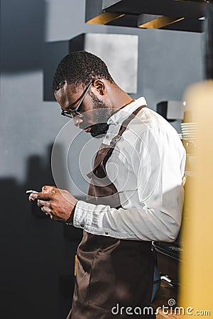 side view of young african american bartender using smartphone Stock Photo