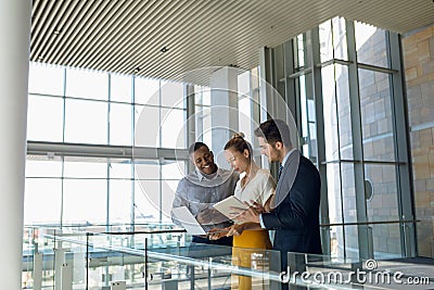 Business colleagues standing in modern office lobby using computers Stock Photo