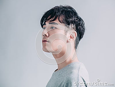 Side view of young asian handsome man isolated on gray background Stock Photo