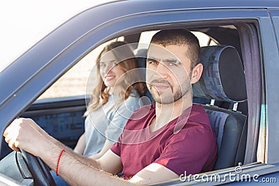 Side view of young beautiful couple has trip in car, look at camera, being in their automobile, enjoy high speed. Family cover Stock Photo