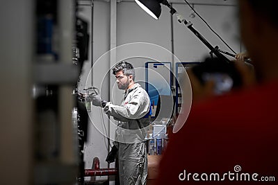 Side view on young handsome caucasian guy in uniform choosing appropriate colour for car dyeing Stock Photo