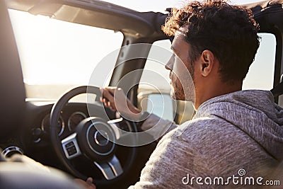 Side view of young Hispanic man driving with sunroof open Stock Photo
