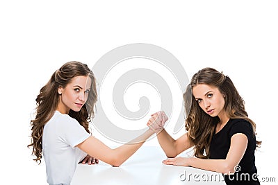 side view of young twins armwrestling at table and looking at camera Stock Photo