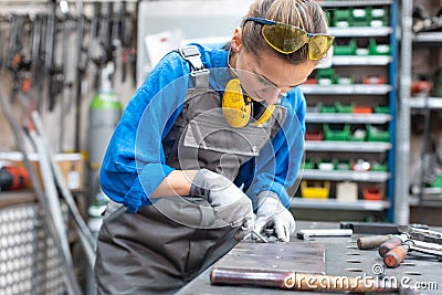 Sideview of worker woman marking piece of metal Stock Photo