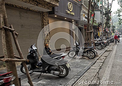 Sidewalk covered with parked motorcycles in Hanoi, Vietnam Editorial Stock Photo