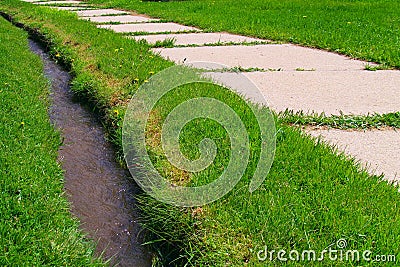 Sidewalk and ditch in grass Stock Photo