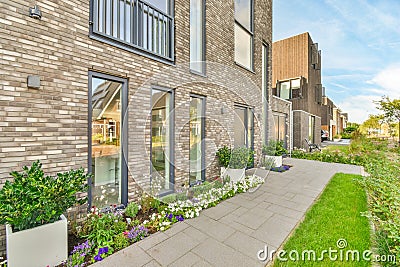 a sidewalk in front of a brick building with flowers Editorial Stock Photo