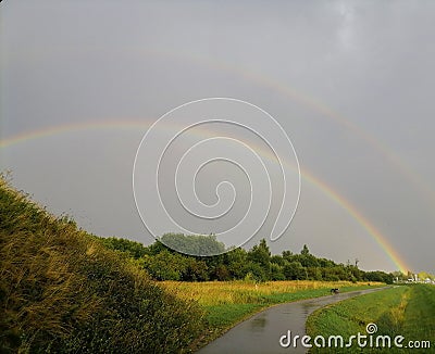 Sidewalk near highway. Rainbow in gray sky. Stock Photo