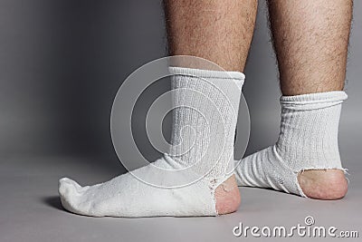 Sideways standing feet with white socks and a big hole Stock Photo