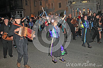 SIDMOUTH, DEVON, ENGLAND - AUGUST 10TH 2012: A group of musicians and clog dancers dressed in mauve and green and holding their Editorial Stock Photo