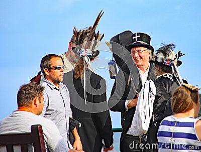 SIDMOUTH, DEVON, ENGLAND - AUGUST 5TH 2012: Three Morris dancers chat to passers by on the Esplanade Editorial Stock Photo