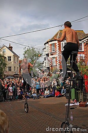 SIDMOUTH, DEVON, ENGLAND - AUGUST 5TH 2012: Two street jugglers and entertainers perform with unicycles and fire clubs in the town Editorial Stock Photo