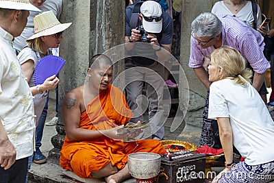 Siem Reap, Cambodia - 14 April 2018: Cambodian buddhist monk reading mantra for tourist in Angkor Wat temple. Editorial Stock Photo