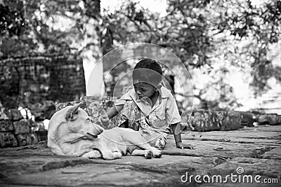 Siem Reap, Cambodia - September 12, 2010: Cambodian boy near some ruins playing with his dog Editorial Stock Photo