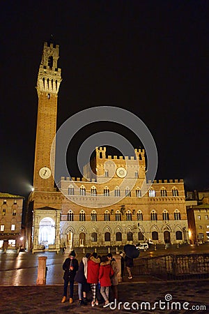 Siena by night. Piazza del Campo and Tower del Mangia illuminated..Tourists in the square. Editorial Stock Photo