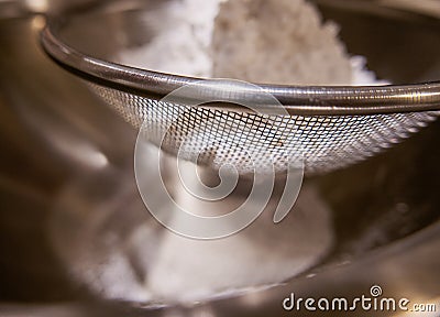 Sieving flour powder into a bowl. Stock Photo