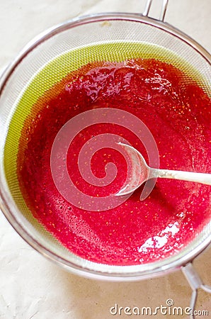 Sieving raspberry puree Stock Photo