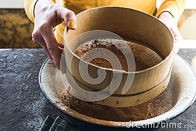 Sifting cocoa into a bowl with flour view from the side Stock Photo