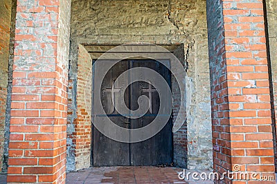 Medieval lutheran church entrance, brick pylons, hand carved cross on the door. Editorial Stock Photo