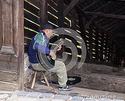 The street guitar player plays the guitar near the entrance to the tunnel, leading to the old town of Sighisoara in Romania Editorial Stock Photo