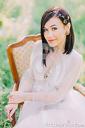 The sight of the woman in spring white dress, with hair accessories and the tattoos on her chest and stomach, sitting on Stock Photo