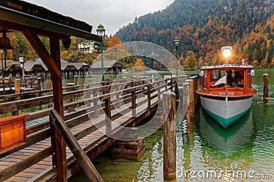 Sightseeing boat parking by a wooden pier at beautiful lakeside in a misty foggy morning on Lake Konigssee Stock Photo
