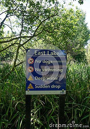 sign board;A sign with No dogs; No swimming and deep water in a park Editorial Stock Photo