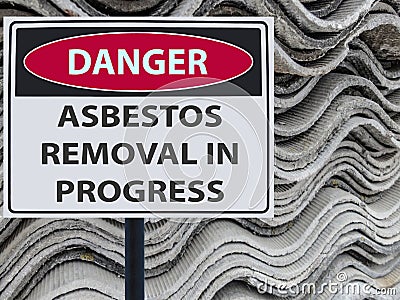 Sign danger asbestos removal in progress and a stack of sheets roof of asbestos. Stock Photo