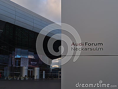 Sign in front of main entrance of futuristic Audi Forum Neckarsulm operated by automotive manufacturer Audi. Editorial Stock Photo