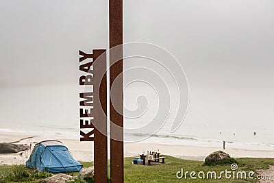 Sign Keem bay in foreground. Blue tent and empty beach, morning fog over the ocean in the background Editorial Stock Photo