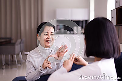 Sign language specialist talking with elderly patient deaf hearing and showing hand gestures Stock Photo