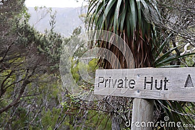 A timber sign in wilderness with the text 'private hut' directing to hidden accommodation in the bush Stock Photo