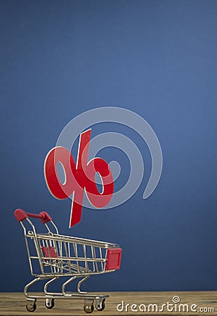 Sign percentages falling into shopping cart on dark blue background Stock Photo