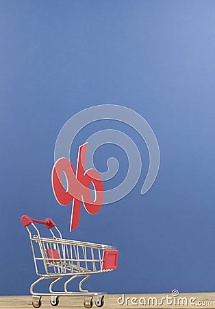 Sign percentages falling into shopping cart on dark blue background Stock Photo