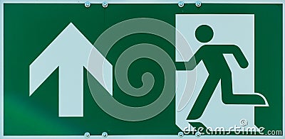 Sign with the pictogram of a walking person and an arrow in white on a green background, indication of an escape route in case of Stock Photo