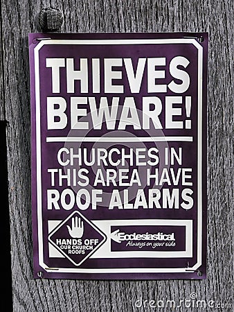 Sign reading Thieves beware, churches in this area have roof alarms. Hands off our church roofs. Editorial Stock Photo